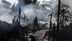 A firefighter battles a blaze at a business establishment, exemplifying the need to 'Prepare Your Business for Disaster' in an urban Australian setting