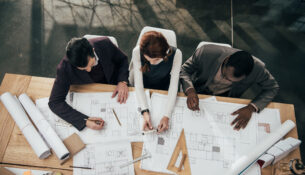 High Angle View Of Team Of Architects Working Together With Plans At Office